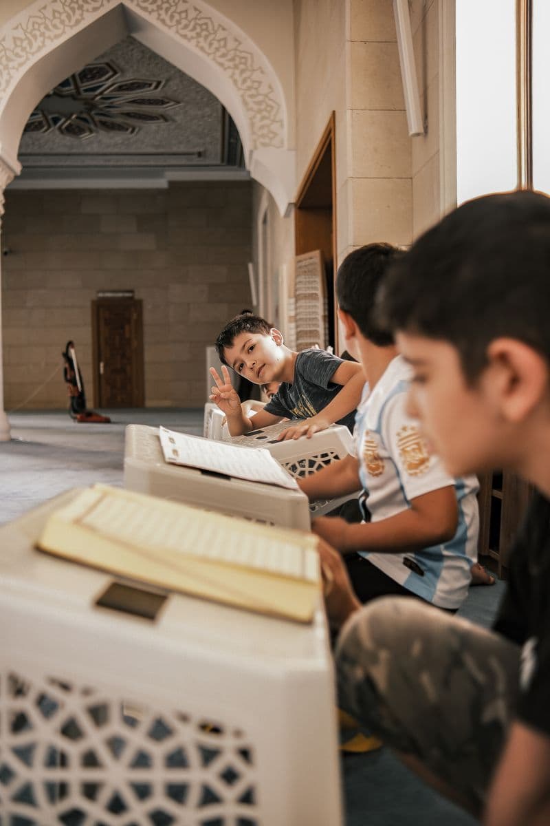 A group of children in traditional attire reading religious texts
