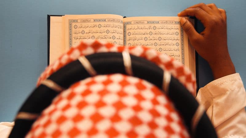 A person reading an open Quran, viewed from above