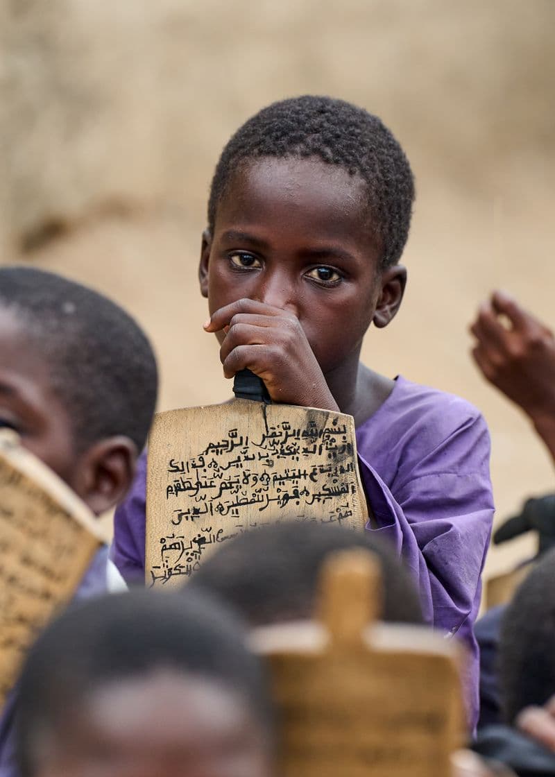 A person in traditional attire reading an open Quran, viewed from above